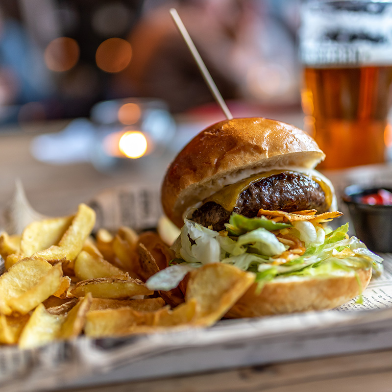 A delicious tavern burger with chips and a beer.