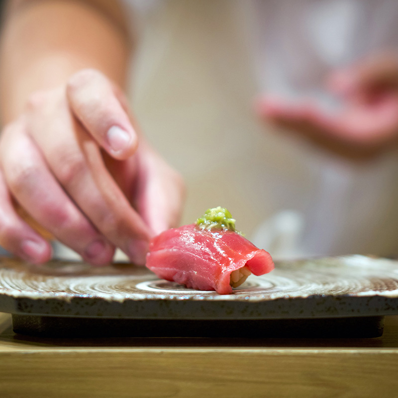 A sushi chef prepares a piece of sashimi.